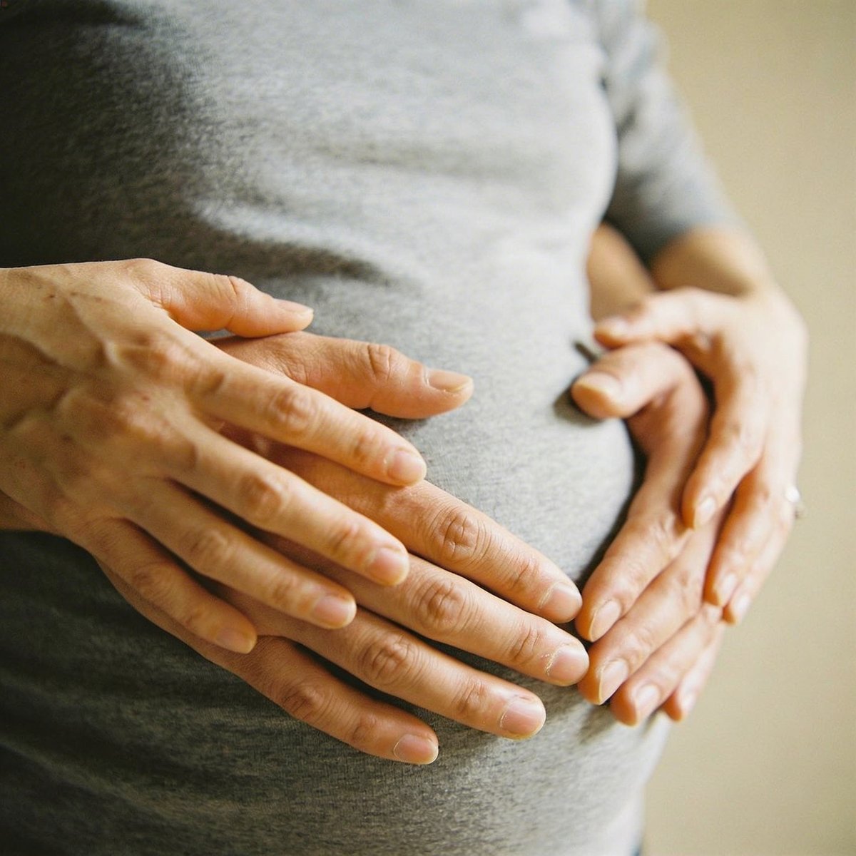 Händer formade som ett hjärta på gravid mage under fotografering